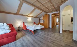 Appartements Living Saalbach في سالباخ هينترغليم: غرفة معيشة بها سريرين وأريكة حمراء