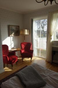 a bedroom with two chairs and a table and a window at Kastanjelund in Yngsjö