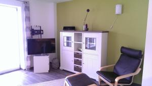 - un salon avec une télévision et une chaise dans l'établissement Ammergauer Vier Jahreszeiten, à Bad Kohlgrub