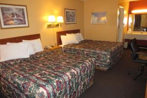 a hotel room with two beds and a chair at Economy Inn & Suites Joplin in Joplin