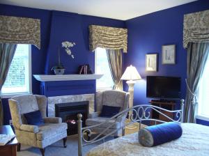 Schlafzimmer mit blauen Wänden, einem Bett und einem Kamin in der Unterkunft The Beacon Inn at Sidney in Sidney