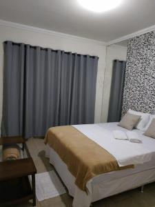 um quarto com uma cama grande e cortinas cinzentas em Residência Cidade Verde 4 em Maringá