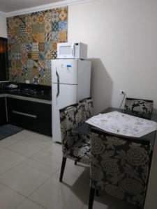 uma cozinha com um frigorífico branco, uma mesa e cadeiras em Residência Cidade Verde 4 em Maringá