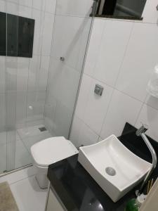 uma casa de banho branca com um lavatório e um WC em Residência Cidade Verde 4 em Maringá