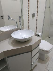 uma casa de banho com um lavatório branco e um WC. em Residência Cidade Verde 4 em Maringá