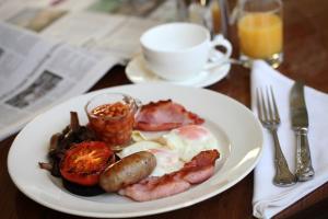 un plato de desayuno con huevos, salchichas y tocino en Ascot House, en Harrogate