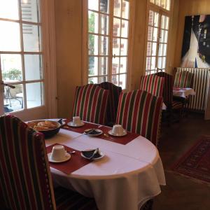 a dining room with a table and chairs and windows at La Villa L'Argentine in Cabourg +20 photos