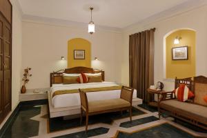 ein Schlafzimmer mit einem Bett, einem Stuhl und einem Sofa in der Unterkunft The Haveli Hari Ganga by Leisure Hotels in Haridwar