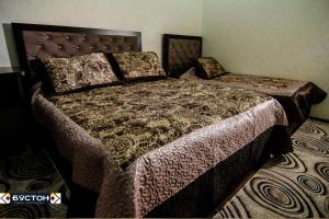 ein Schlafzimmer mit einem großen Bett mit einer Bettdecke und Kissen in der Unterkunft Hotel Buston in Chkalovsk