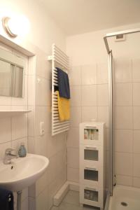 a white bathroom with a sink and a shower at Ferienwohnung Bunte Kuh Wangerooge in Wangerooge