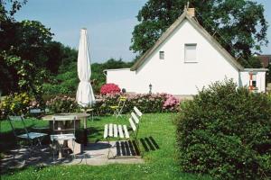 un patio con mesa, sombrilla y sillas en Ferienhof Schön, en Zempin