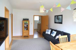 a living room with a black couch and a table at Ferienwohnung Bunte Kuh Wangerooge in Wangerooge