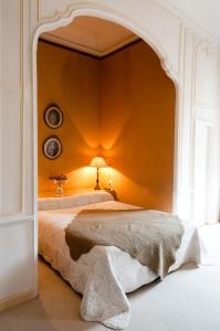 een slaapkamer met een bed met een oranje muur bij Château d'Arpaillargues - TERITORIA in Arpaillargues-et-Aureillac