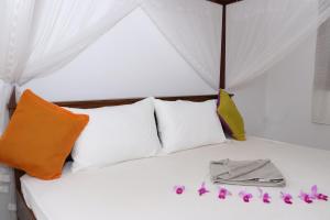 Una cama con almohadas blancas y flores púrpuras. en Great yeheni villa, en Hikkaduwa