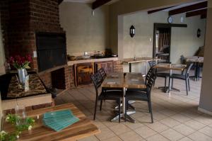 a kitchen with tables and chairs and a fireplace at Crystal Rose Lodge & Spa in Krugersdorp