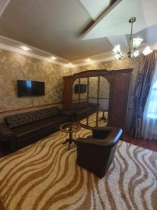 a living room with a couch and a chair and a television at Hotel Alberia in Pyatigorsk