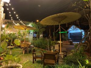 an outdoor patio with tables and umbrellas at night at Elliebum Boutique Hotel in Chiang Mai
