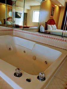 Jets Motor Inn في كوينز: حوض استحمام في الحمام مع مرآة كبيرة