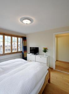 Un dormitorio con una gran cama blanca y una ventana en Hotel-Restaurant zum Gade, en Lenk