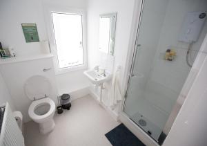 a white bathroom with a toilet and a shower at Old School Wolverton in Milton Keynes