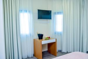 un dormitorio con cortinas blancas y una mesa con flores. en Villamar Style Maison, en Nazaré