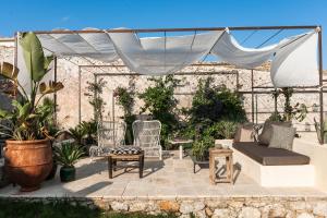 een patio met stoelen, een bank en een luifel bij Dimora delle Balze in Noto