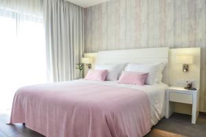 a bedroom with a large white bed with pink pillows at Villamar Style Maison in Nazaré
