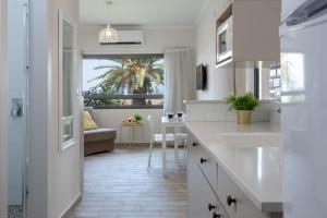 a kitchen with white cabinets and a living room at Holiday Village Kibbutz Mizra in Mizra‘
