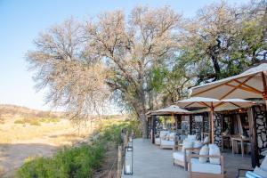 a restaurant with white chairs and umbrellas on a patio at Last Word Kitara in Klaserie Private Nature Reserve