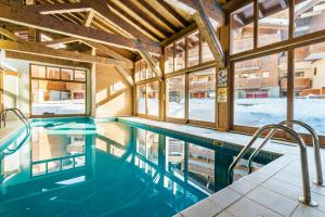 uma piscina num edifício com janelas em travelski home premium - Résidence Les Chalets d'Edelweiss 4 étoiles em Plagne 1800
