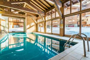 a swimming pool in a building with windows at travelski home premium - Résidence Les Chalets d'Edelweiss 4 étoiles in Plagne 1800