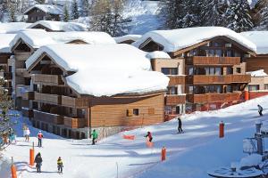 um grupo de pessoas a esquiar em frente a um alojamento de esqui em travelski home premium - Résidence Les Chalets d'Edelweiss 4 étoiles em Plagne 1800