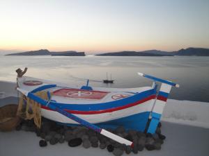 a boat sitting on rocks in front of the water at Kokkinos Villas in Akrotiri +187 photos