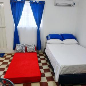 1 dormitorio con 2 camas, cortinas azules y alfombra roja en Apartamento Mattos en Taganga