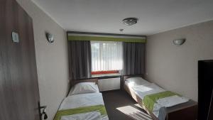 a room with two beds and a window at Restauracja i hotel Pod Kasztanami in Opole