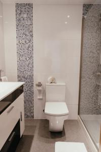 a white bathroom with a toilet and a shower at Hauzify I Apartament Marina in Torredembarra