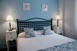 a bedroom with a large bed with blue walls and two lamps at Hauzify I Apartament Marina in Torredembarra