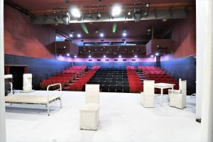 un auditorium avec des sièges rouges et des tables et chaises blanches dans l'établissement Hotel Liberty Theatre, à Tbilissi