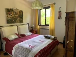 Un dormitorio con una cama con una manta roja y una ventana. en La casa del Pino Argentato, en Ateleta