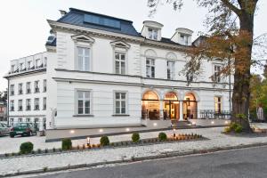 ein weißes Haus mit einem Baum davor in der Unterkunft Red Baron Hotel & Restaurant in Świdnica