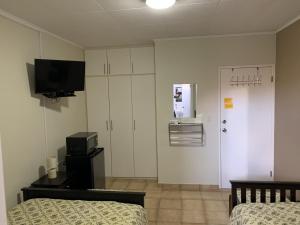 ウィレムスタッドにあるEve's Residenceのベッド2台、壁掛けテレビが備わる客室です。