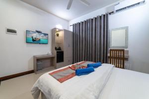 a bedroom with a large white bed and a tv at Nala Veli Villa in Ukulhas