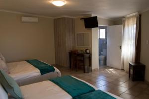 a hotel room with two beds and a bathroom at Crystal Rose Lodge & Spa in Krugersdorp