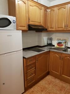 a kitchen with wooden cabinets and a white refrigerator at Soldeu Paradis Tarter Mig in El Tarter