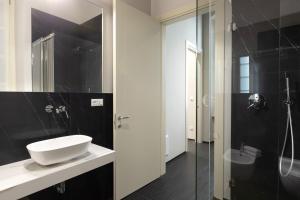La salle de bains en noir et blanc est pourvue d'un lavabo et d'une douche. dans l'établissement Salina Luxury Suites, à Parme