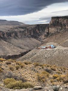 une maison au milieu d'un désert avec une montagne dans l'établissement La Posta de los Toldos, à Perito Moreno