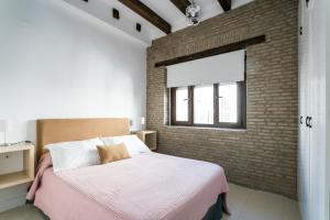 1 dormitorio con cama y pared de ladrillo en RR Apartamentos Arrayan 23, en Sevilla