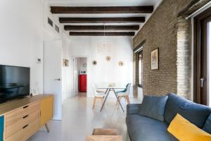 een woonkamer met een blauwe bank en een bakstenen muur bij RR Apartamentos Arrayan 23 in Sevilla