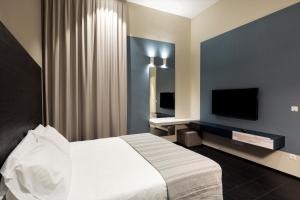 - une chambre avec un lit et une télévision à écran plat dans l'établissement Salina Luxury Suites, à Parme
