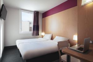 une chambre d'hôtel avec 2 lits et un ordinateur portable sur un bureau dans l'établissement B&B HOTEL Bordeaux Centre Bègles, à Bègles